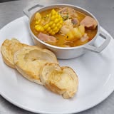 Papi’s hearty soup served with bread on a gray wooden table